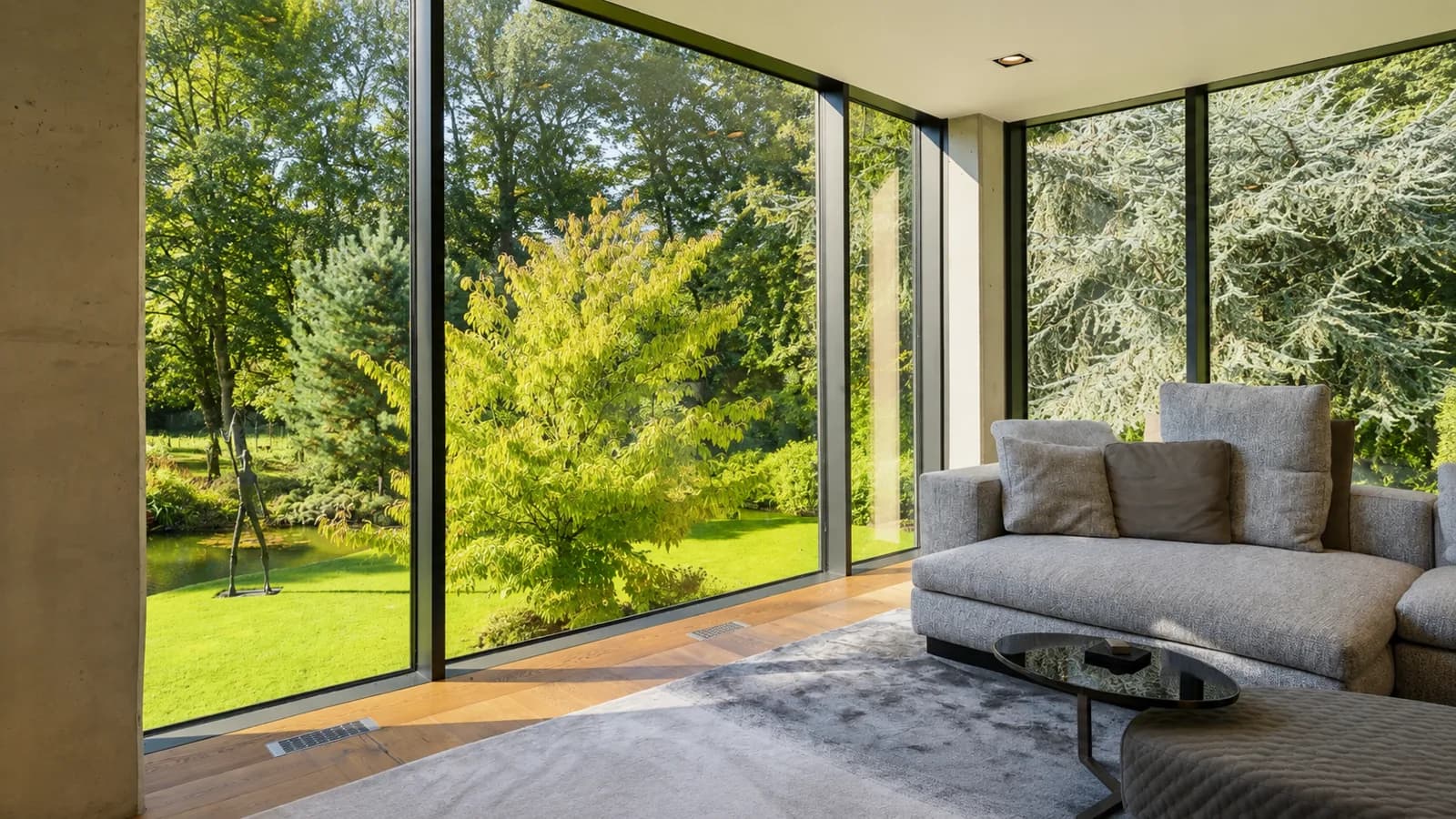 Verglaster Wohnraum mit Sofa und bodentiefem Fenster zum Garten, Hartenfels