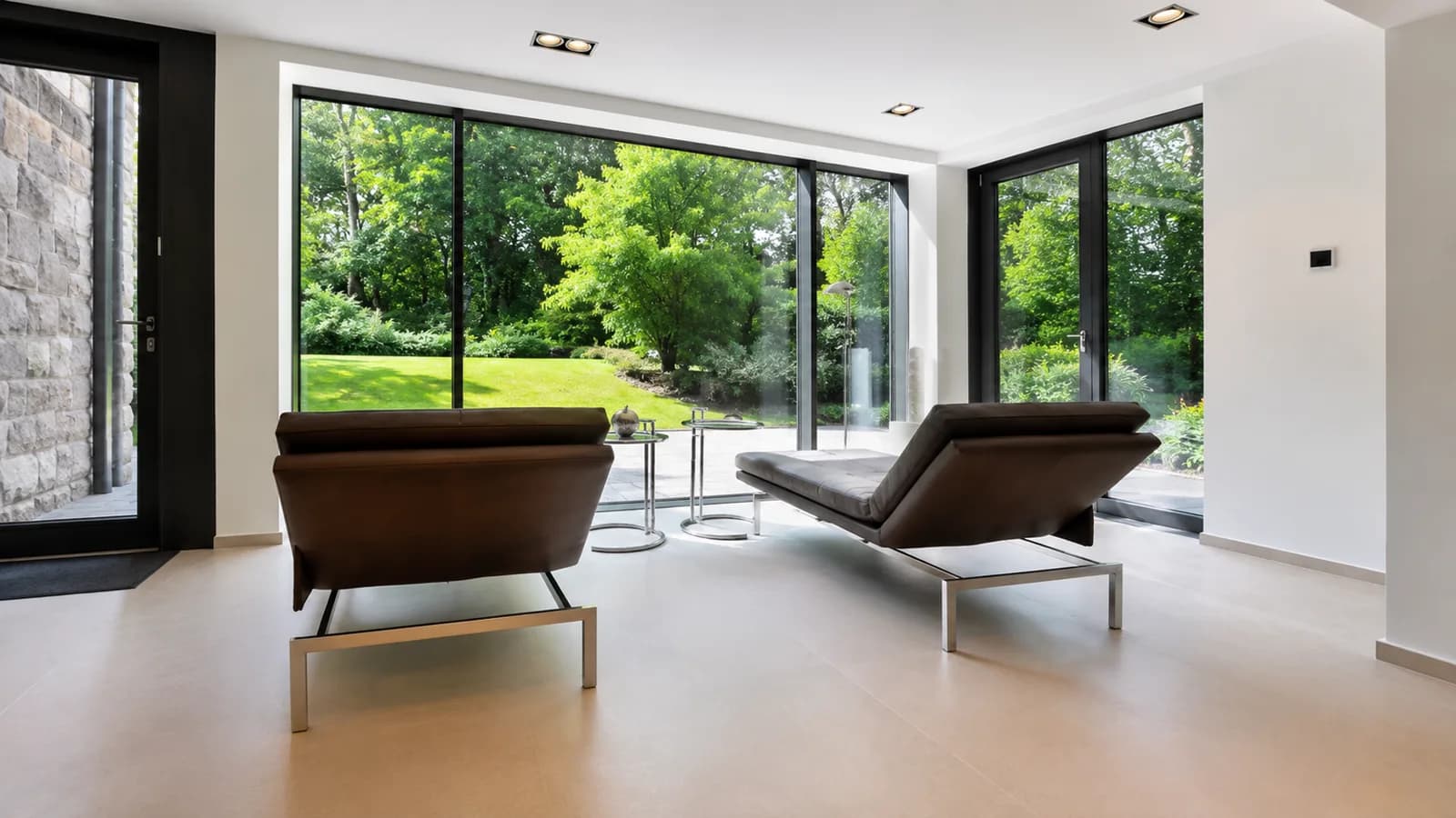Zwei Leder-Liegen vor raumhoher Glasfront mit Zugang zum Garten, Hartenfels