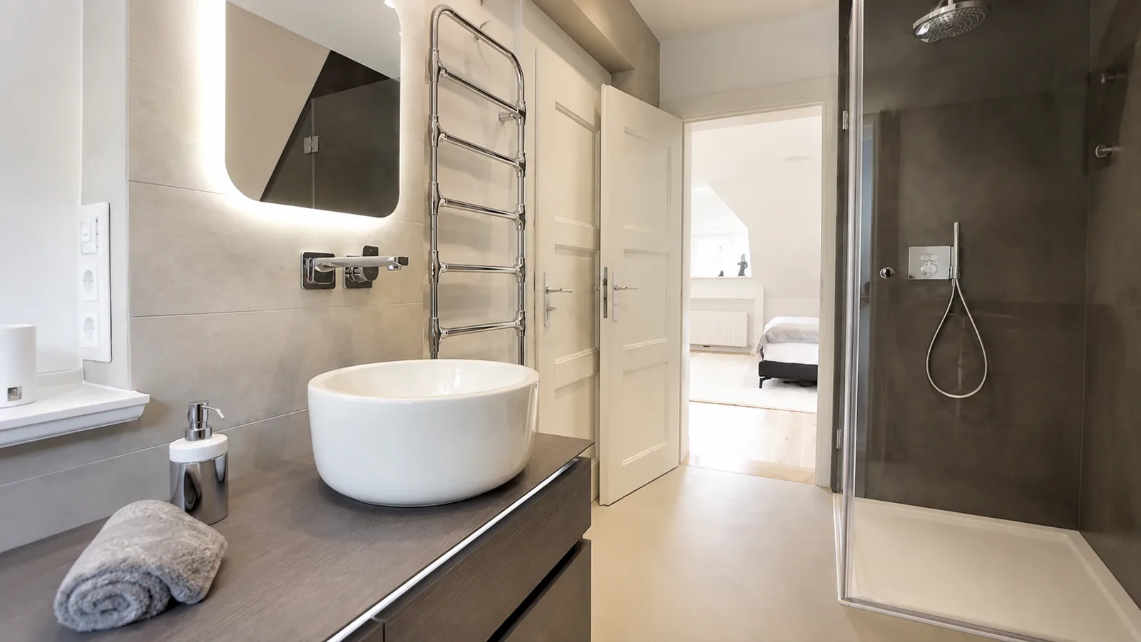 Badezimmer mit Aufsatzwaschbecken, beleuchtetem Spiegel und ebenerdiger Dusche, Hartenfels