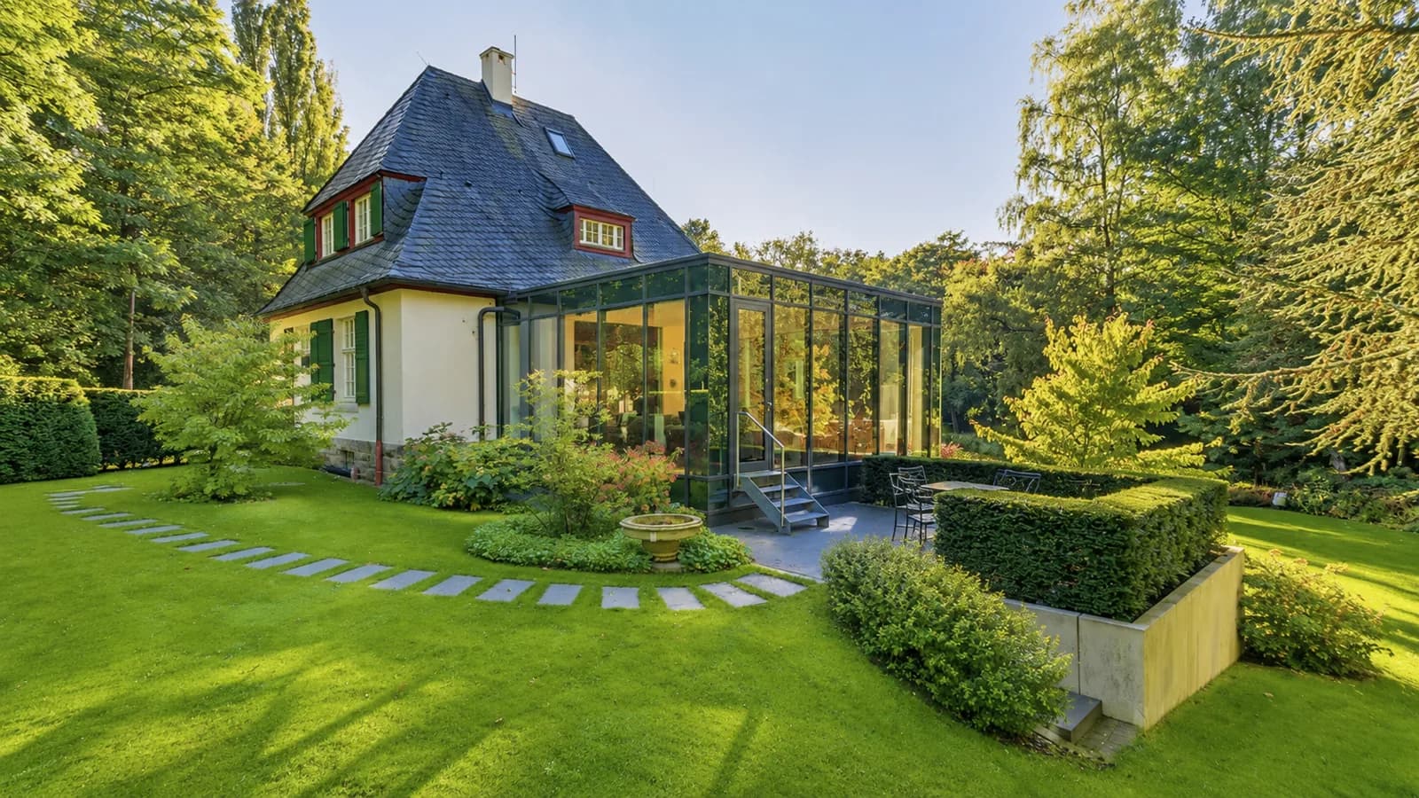 Gartenseite des Gärtnerhauses mit Wintergarten, Trittsteinweg und Brunnen im Abendlicht, Hartenfels