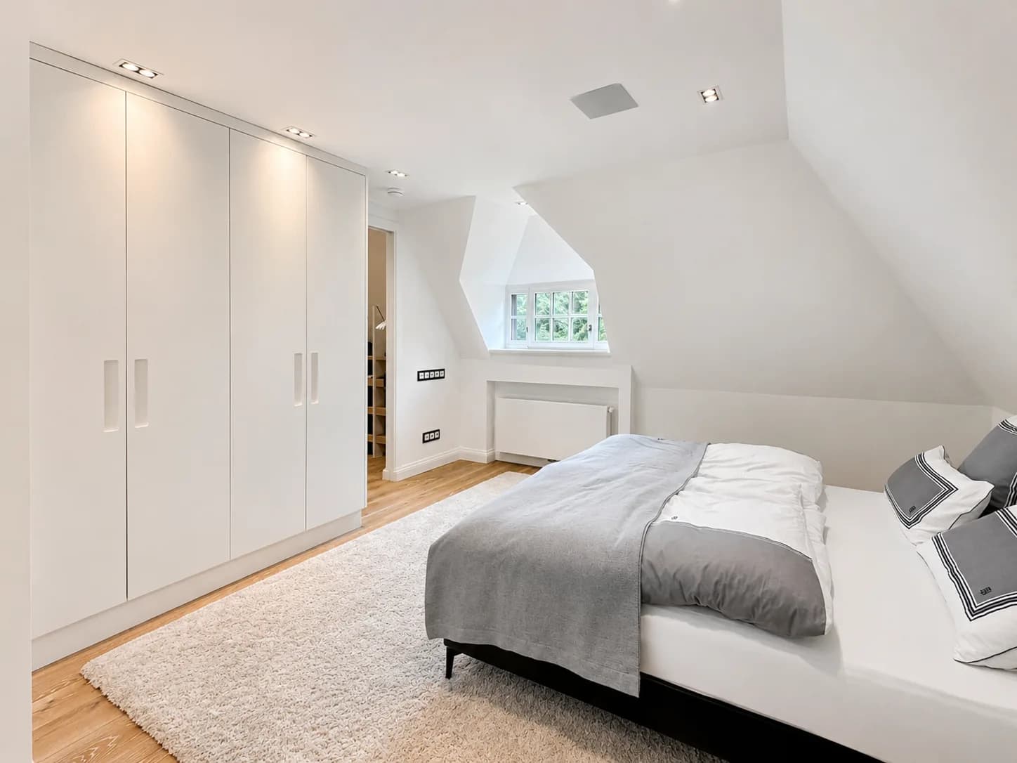 Schlafzimmer unterm Dach mit weißer Einbauschrankwand und Gaubenfenster, Hartenfels