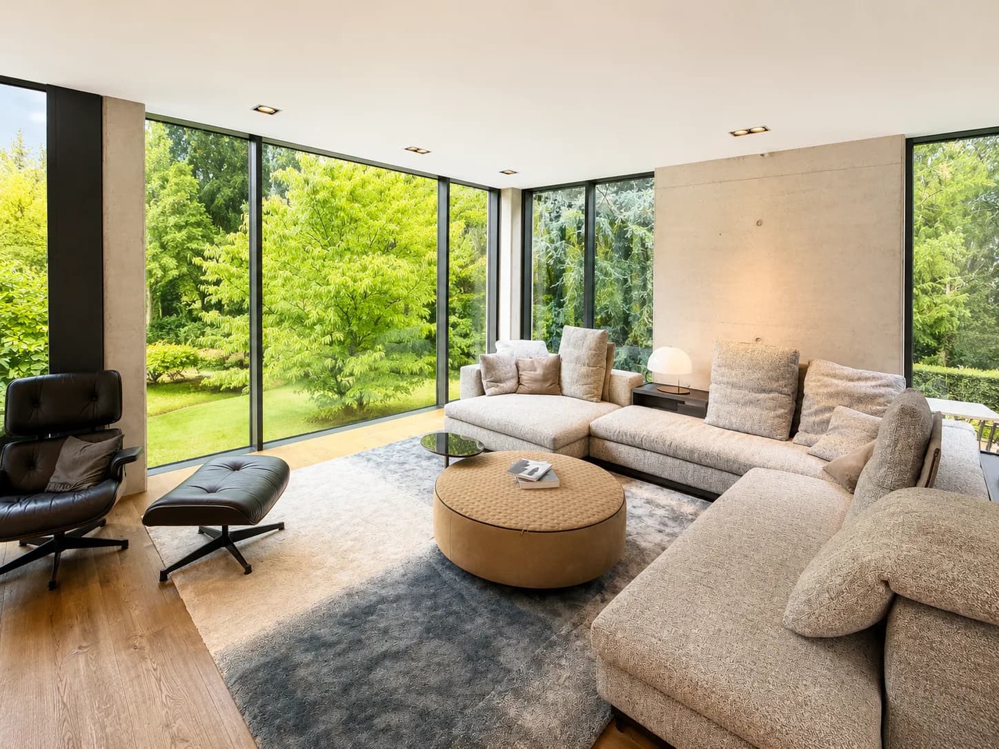 Wohnraum mit heller Polsterlandschaft, Loungesessel und raumhoher Verglasung zum Garten, Hartenfels