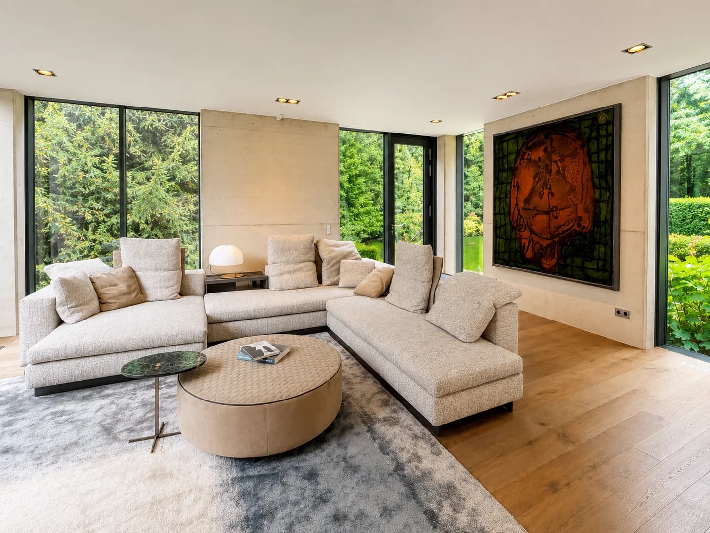Wohnraum mit Sofalandschaft, Kunstwerk und Panoramafenstern zum Garten, Hartenfels
